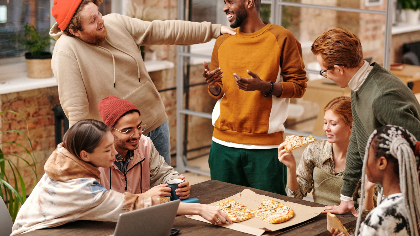group of people eating pizza and talking