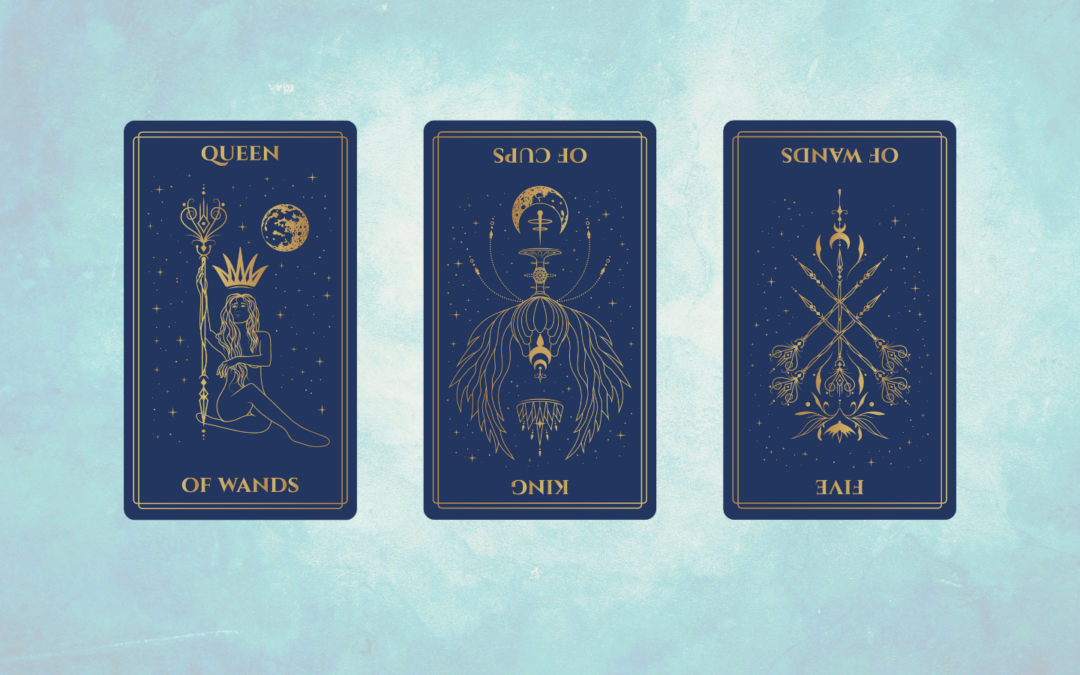 A tarot spread against a soft blue textured background featuring three cards. From left to right: the Queen of Wands upright, the King of Cups reversed, and the Five of Wands reversed. Each card has a navy background with gold line art and celestial designs, including stars, moons, and decorative borders. The Queen of Wands depicts a figure seated confidently holding a staff, the King of Cups reversed shows an intricate, symmetrical design with a central chalice, and the Five of Wands reversed displays crossed wands with ornate floral details.